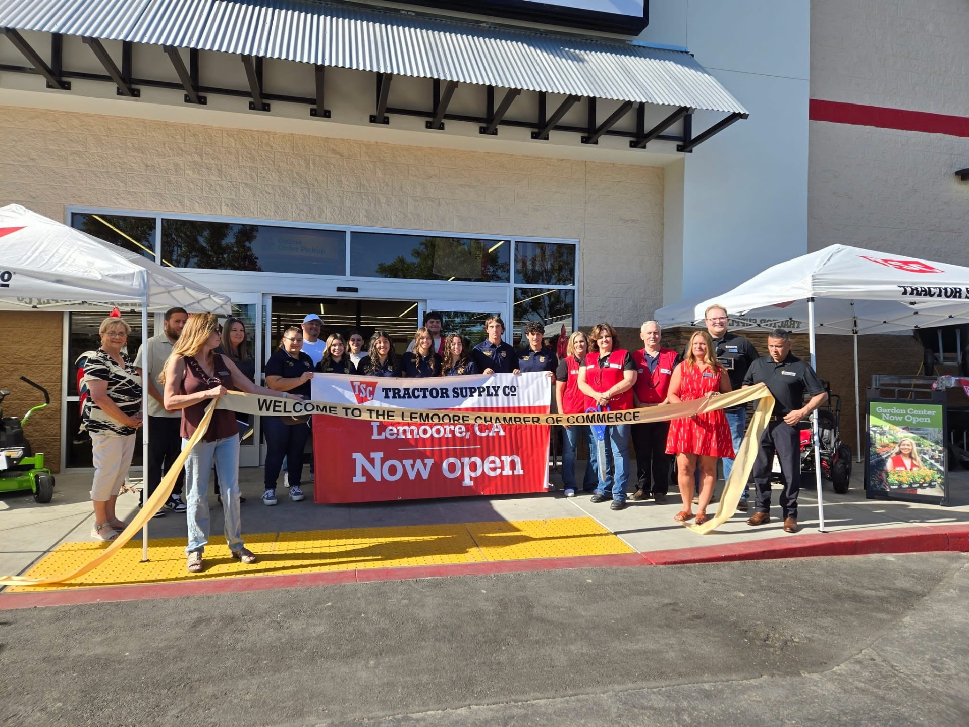 A Chamber ribbon cutting with the giant scissors and a crowd